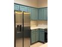 Clean kitchen featuring stainless steel refrigerator and teal cabinets at 1209 Jonah Dr, North Port, FL 34289