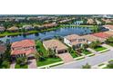 Aerial view of home with beautiful landscaping, lake view, and a brick driveway in an upscale community at 13220 Swiftwater Way, Lakewood Ranch, FL 34211