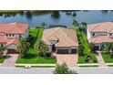 Aerial view of tile roof home with beautiful landscaping, two car garage, and a backyard overlooking a lake at 13220 Swiftwater Way, Lakewood Ranch, FL 34211