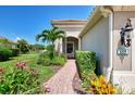Inviting front entrance with a brick walkway and colorful flowering plants at 1375 Backspin Dr, Englewood, FL 34223