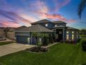 Beautiful two-story home with lush landscaping and a well-manicured lawn at twilight at 2347 123Rd E Pl, Parrish, FL 34219