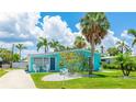 Inviting turquoise home showcasing lush greenery, a palm tree, and a bright, clear sky with fluffy clouds at 2713 Avenue C, Holmes Beach, FL 34217