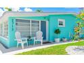 Close up of a cozy turquoise home's entryway, featuring seating and manicured landscaping at 2713 Avenue C, Holmes Beach, FL 34217