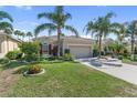 Charming single-story home featuring a manicured lawn, colorful flower beds, and a welcoming two-car garage at 305 Siena Vista Pl, Sun City Center, FL 33573