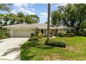 Charming single-story home boasts a tile roof, manicured lawn, and vibrant landscaping under a blue sky at 4353 Indian Point Trl, Sarasota, FL 34238
