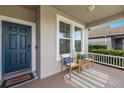 Cozy front porch with a blue front door, welcome mat, and two comfortable chairs and side table at 4617 Garden Arbor Way, Bradenton, FL 34203