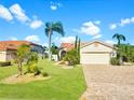 Charming single-story home with a well-maintained lawn, lush landscaping and a brick driveway under a clear sky at 4907 Kilty E Ct, Bradenton, FL 34203
