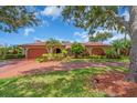 Inviting home featuring a red tile roof, arched entryway, mature trees, and lush landscaping at 5349 Everwood Run, Sarasota, FL 34235