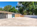 A spacious backyard featuring a concrete patio, wooden privacy fence, and a screened in room at 5948 Mirror Lake Rd, Sarasota, FL 34238