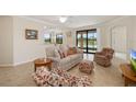 Bright living room with comfortable seating, tiled floors, and sliding glass doors with a lake view at 6923 Grand Estuary Trl # 101, Bradenton, FL 34212