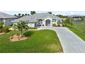 Well maintained home with a lush green lawn, palm trees and long driveway leading to a two-car garage at 8106 Arlewood Cir, Port Charlotte, FL 33981
