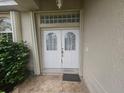 Inviting entryway with decorative glass block above double doors and tiled front porch at 9926 Gulfstream Blvd, Englewood, FL 34224
