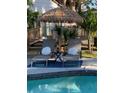 Relaxing poolside lounge area featuring comfortable lounge chairs, a tiki umbrella, and privacy landscaping at 1112 Montezuma Dr, Bradenton, FL 34209
