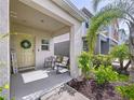 Cozy front porch with seating, decorative welcome sign, and a cheerful wreath on the bright yellow front door at 12832 Oak Hill Way, Parrish, FL 34219