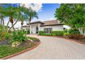 Beautiful home with mature trees and landscaping, a brick paved driveway and a black trim on the windows at 1484 Seafarer Dr, Osprey, FL 34229