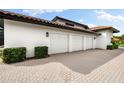 Spacious three-car garage with an extended brick-paved driveway, nestled amongst neatly trimmed shrubs at 1484 Seafarer Dr, Osprey, FL 34229