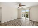 Bright, empty bedroom featuring wood-look floors, ceiling fan, and sliding glass doors to private deck at 2513 Avenue B # B, Bradenton Beach, FL 34217