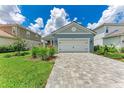A single-story home featuring a well-manicured lawn, gray paver driveway, and a classic white two-car garage door at 2565 Star Apple Way, Sarasota, FL 34240