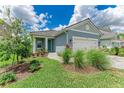 Charming single-story home showcasing lush landscaping, a paver walkway, a white garage door, and teal front door at 2565 Star Apple Way, Sarasota, FL 34240