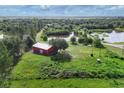 Aerial view of red barn with lush green land and pond in the background at 3045 Logue Rd, Myakka City, FL 34251