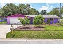 A well-kept, purple single-story home with a fenced yard and mature landscaping at 3240 6Th St, Sarasota, FL 34237
