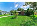 Well-manicured front yard with a young palm tree in front of a charming single-story home with mature trees at 444 Flamingo Dr, Apollo Beach, FL 33572