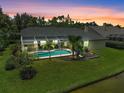 Aerial view of a backyard featuring a screened-in pool, lush lawn, mature landscaping, and a serene pond at 4733 Spring Meadow Ln, Sarasota, FL 34233