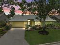 Charming single-story home featuring a well-manicured lawn, a two-car garage, and attractive landscaping with trees at 4733 Spring Meadow Ln, Sarasota, FL 34233