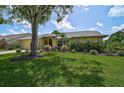 Landscaped front yard with a mature tree shading a single-Gathering home at 4733 Spring Meadow Ln, Sarasota, FL 34233