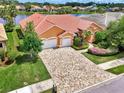 Aerial view of a beautiful orange home with a red tile roof, lush landscaping, and a paver driveway at 4957 Sabal Lake Cir, Sarasota, FL 34238