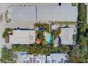 Aerial view of a property with a refreshing pool, vibrant umbrellas, and tropical landscaping at 509 Pine Ave # A, Anna Maria, FL 34216