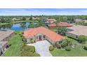 Stunning home with red tile roof, surrounded by lush greenery, manicured lawn, and a serene lake view at 5523 Secluded Oaks Way, Sarasota, FL 34233