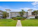 Exterior view of a three-story condo building with white balconies, beautiful landscaping, and a walkway at 6507 Stone River Rd # 304, Bradenton, FL 34203