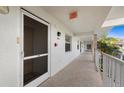 Condo hallway with white walls, screened-in doors, and tiled floors, featuring palm trees in the background at 6507 Stone River Rd # 304, Bradenton, FL 34203