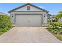 Two-car garage with an brick-paved driveway and manicured shrubs at 6563 Silverstar Dr, Sarasota, FL 34240