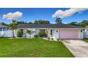 Charming single-story home with a well-manicured lawn, pink garage door, and tasteful landscaping at 912 Ponderosa Pine Ln, Sarasota, FL 34243