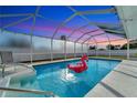 Relaxing enclosed pool area with crystal-clear water and a fun inflatable flamingo under a sunset sky at 912 Ponderosa Pine Ln, Sarasota, FL 34243