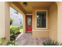 Inviting front porch featuring a red front door with decorative glass and brick pavers at 13805 Posada St, Venice, FL 34293