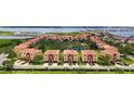A high-angle shot shows terra cotta-roofed townhouses nestled around a scenic pond and lush trees at 1512 3Rd Street E Cir, Palmetto, FL 34221