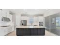 A modern kitchen featuring white cabinets, stainless steel appliances, and a large island with a dark base at 15813 San Lazzaro Ave, Bradenton, FL 34211
