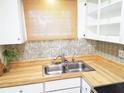 A bright kitchen features white cabinets, butcher block countertops, and a stainless-steel sink at 2155 Wood St # A26, Sarasota, FL 34237