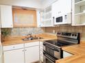 A well-lit kitchen features white cabinets, butcher block countertops, and stainless-steel appliances at 2155 Wood St # A26, Sarasota, FL 34237