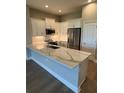 Modern kitchen with white cabinets, stainless steel appliances, and a spacious quartz countertop island at 24803 Buckingham Way, Port Charlotte, FL 33980