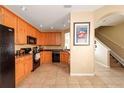 A kitchen featuring wood cabinets, black appliances, tile flooring, and a flamingo art piece at 3698 Parkridge Cir # 26-104, Sarasota, FL 34243