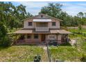 Two-story home with a large front porch and screened-in balcony, nestled amongst mature trees at 5034 257Th E St, Myakka City, FL 34251