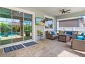 Covered patio with ceiling fan, sliding glass doors, tv and comfortable seating area. Perfect for entertaining at 5750 Long Shore Loop, Sarasota, FL 34238