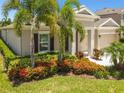 Beautiful home featuring colorful landscaping with palm trees and lush green lawn at 5802 Alabaster Stone Ln, Apollo Beach, FL 33572
