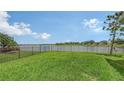 Green backyard with a partial lake view, complimented by black aluminum fencing and lush lawn at 5910 Hevena Ct, Palmetto, FL 34221