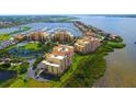 Aerial view of waterfront condo community showcasing marina access, lush greenery, and beautiful waterfront residences at 610 Riviera Dunes Way # 306, Palmetto, FL 34221