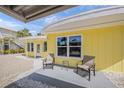 Exterior view of a yellow home, showcasing the outdoor seating area and shell ground cover at 627 Avenida Del Norte, Sarasota, FL 34242